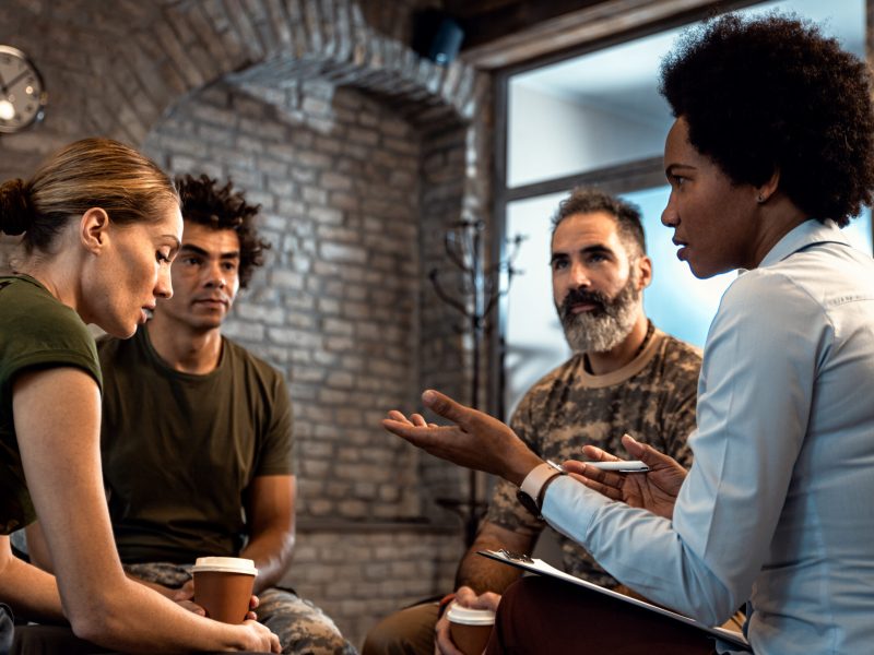 Group of diverse veterans talking during PTSD support group.